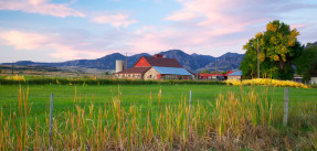 Red barn set against mountain range with sunset sky