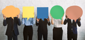 Business people standing in a row holding large communication bubbles over their faces