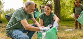 Group of volunteers--old and young--collecting trash in a forest together