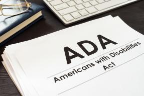 Americans with Disabilities Act ADA paperwork with keyboard, glasses and book