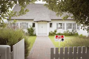 House with for sale sign in yard and open wooden fence