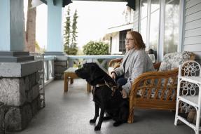 Visually impaired woman sitting with seeing eye dog on porch