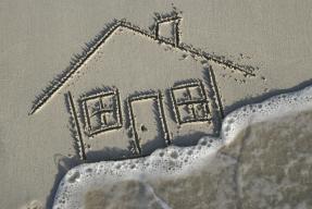 House in sand on beach flooded by wave