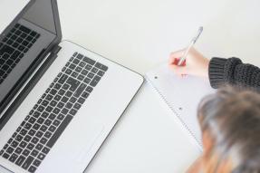 Woman in front of a laptop taking notes
