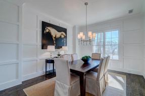 An all white dining room with a painting of a horse prominently displayed on one wall.