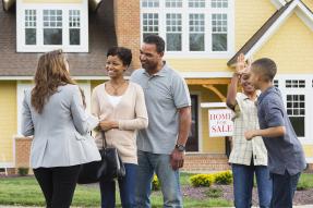 African-American family with agent in front of home