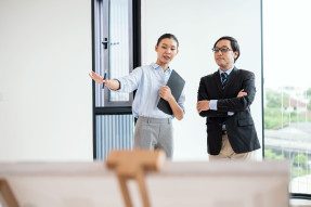 Female Real estate agent showing a homes for sale to senior Japanese business man