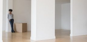 woman leaning on pillar in empty apartment