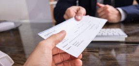 Businessperson Giving Check To Colleague