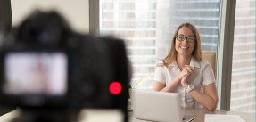 Smiling businesswoman talking on camera, recording business video blog