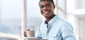 man drinking coffee and looking at tablet