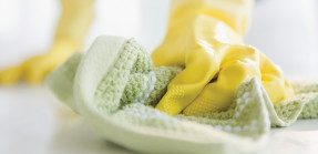 gloved hands cleaning surface with cloth