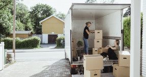 Two women loading boxes into moving truck.