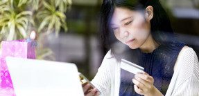 Woman holding credit card in front of computer