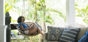 Woman sitting in hanging chair in vacation home