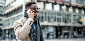 African American businessperson walking through city talking on the phone