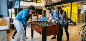 Four coworkers playing foosball at an office