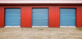 A picture of three blue self-storage unit doors next to each other, attached to the same red structure.