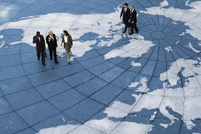 Business professionals walking across a world map floor