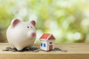Ceramic piggy bank and house on a shelf with coins