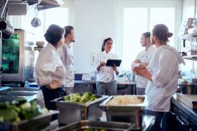 Chef discussing with team in industrial kitchen