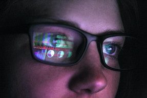 Woman in glasses with computer reflection in lens 