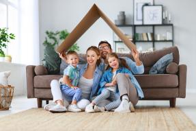 Family in a living room holding a cardboard roof