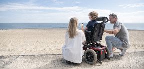 Parents with child in wheelchair at beach