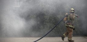 Firefighter carrying hose on sidewalk