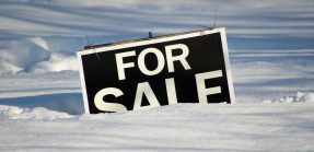 For sale sign buried in snow