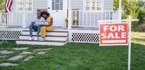 Couple on porch with sold sign