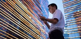man with smartphone in front of commercial building lit up