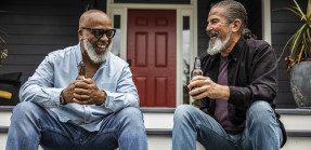 Neighbors laughing on front steps of house