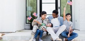 Military family in front of house holding American flags