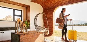 Woman with luggage using her phone at vacation home