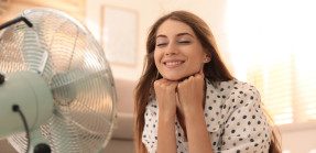 Woman sitting in front of fan in home
