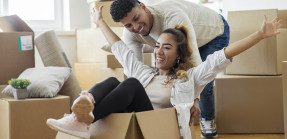 Happy couple with moving boxes in new home