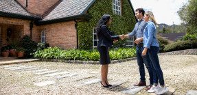 Real estate agent meeting clients in front of house