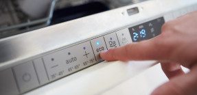 Person pressing the "eco" button on energy efficient appliance