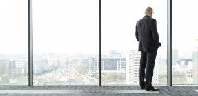 Businessman on empty office floor looking out of window