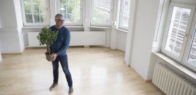 Man holding plant in empty apartment