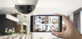 Security camera in home with person watching security footage on iphone