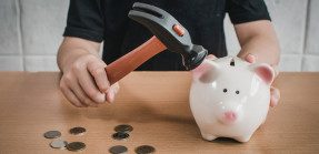 Breaking piggy bank with hammer