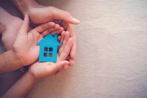 Hands holding a blue cutout of a house