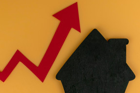 llustration: Rising red line graph arrow next to black house shape on yellow background