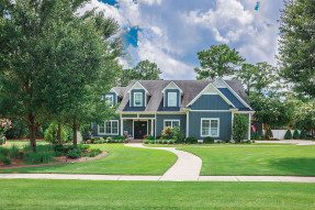 Large blue Craftsman house with large front lawn and trees