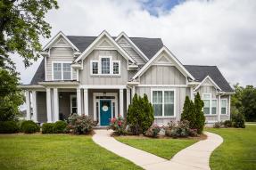 Large gray house with blue door and big lawn