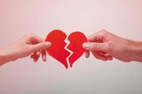 Male and female hands pulling a paper heart apart