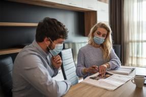 Man and woman wearing masks in office, going over papers