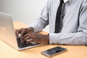 Man sitting at a desk, typing on a laptop